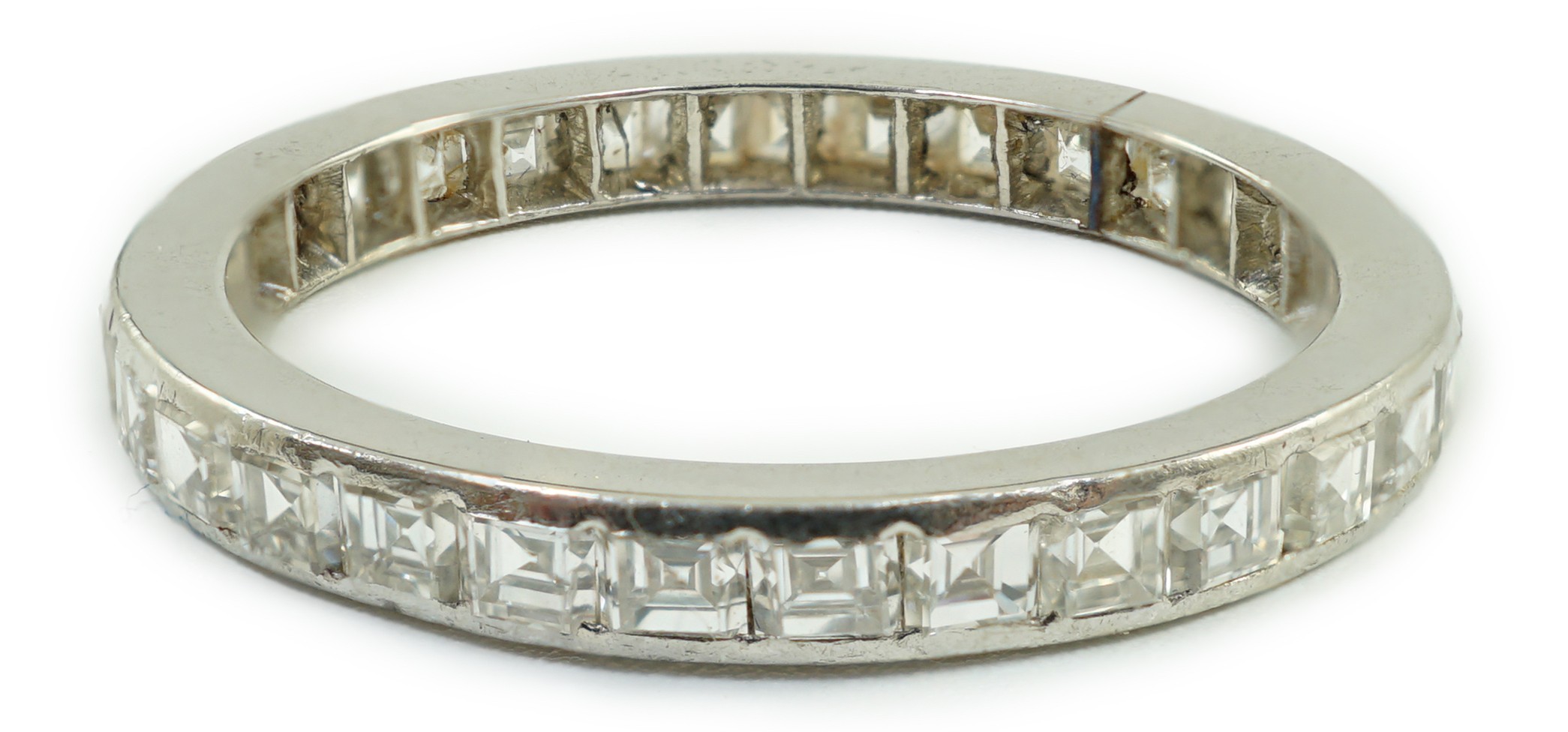 A white metal and square cut diamond set full eternity ring, size M/N, gross weight 2.3 grams.